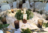 Centro con velones y ramaje, acompañado de piñas secas. Decoración floral de restaurante para una boda. Flores boda. Rebolledo Floristas.