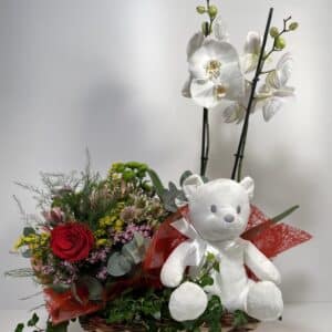 composición para San Valentín de orquídeas, bouquet silvestre y peluche en una cesta de mimbre
