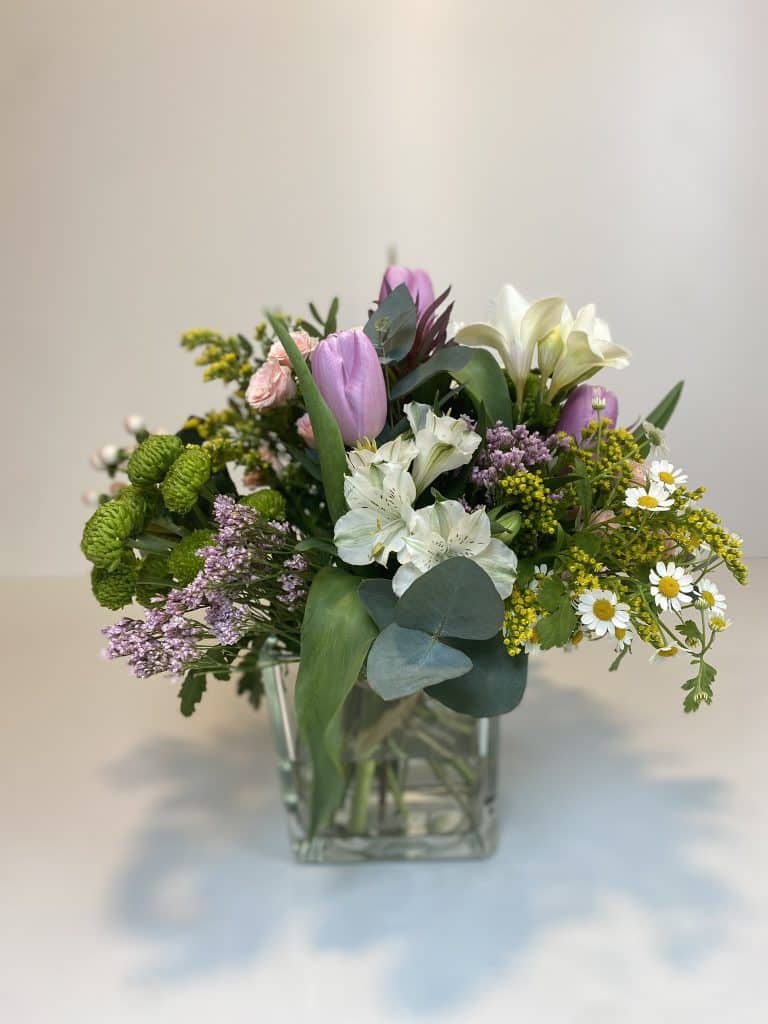 Bouquet silvestre en jarrón de cristal, flores en colores variados.