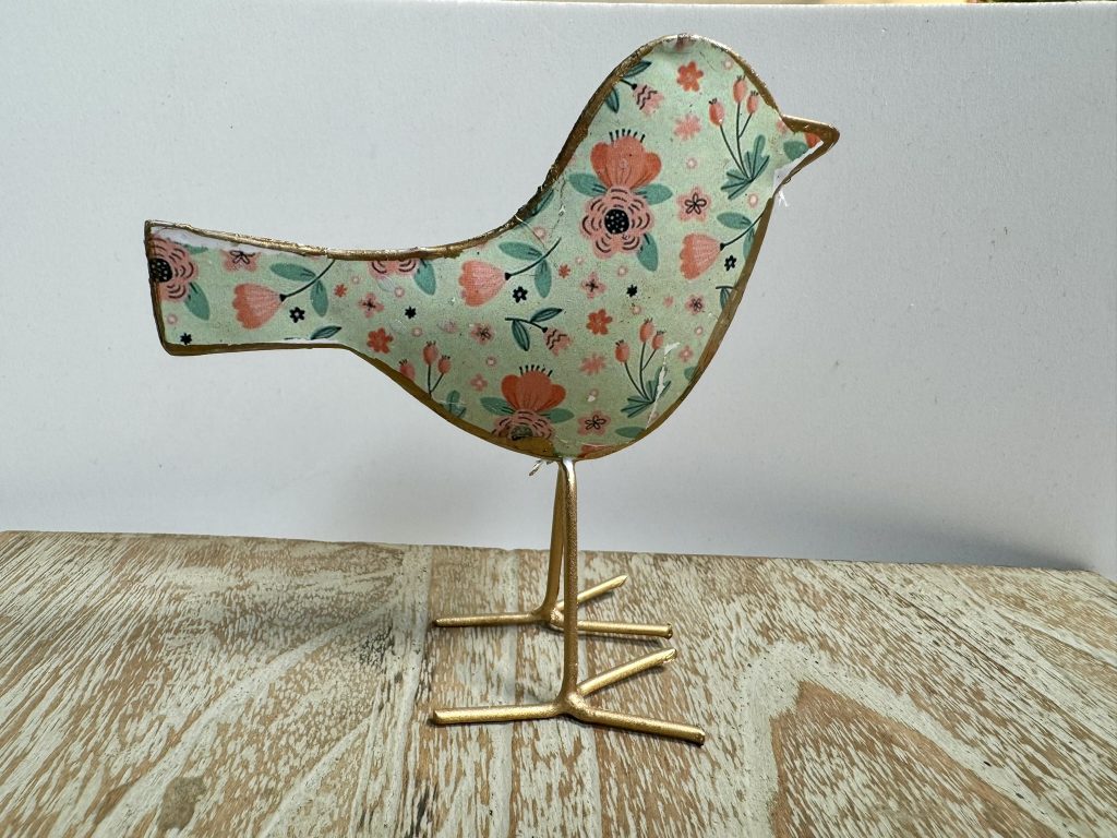 Ave de latón con el fondo blanco y diseño de flores coloridas.