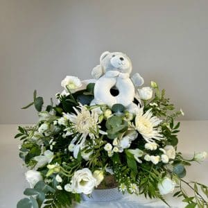 Baúl con flores variadas en tonos blancos con peluche