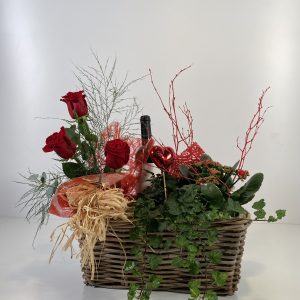 Composición de una cesta para San Valentín rectangular con 3 rosas rojas naturales, hiedra y un kalanchoe de color variado.