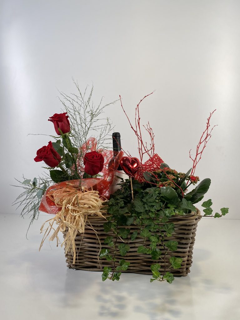 Composición de una cesta para San Valentín rectangular con 3 rosas rojas naturales, hiedra y un kalanchoe de color variado.