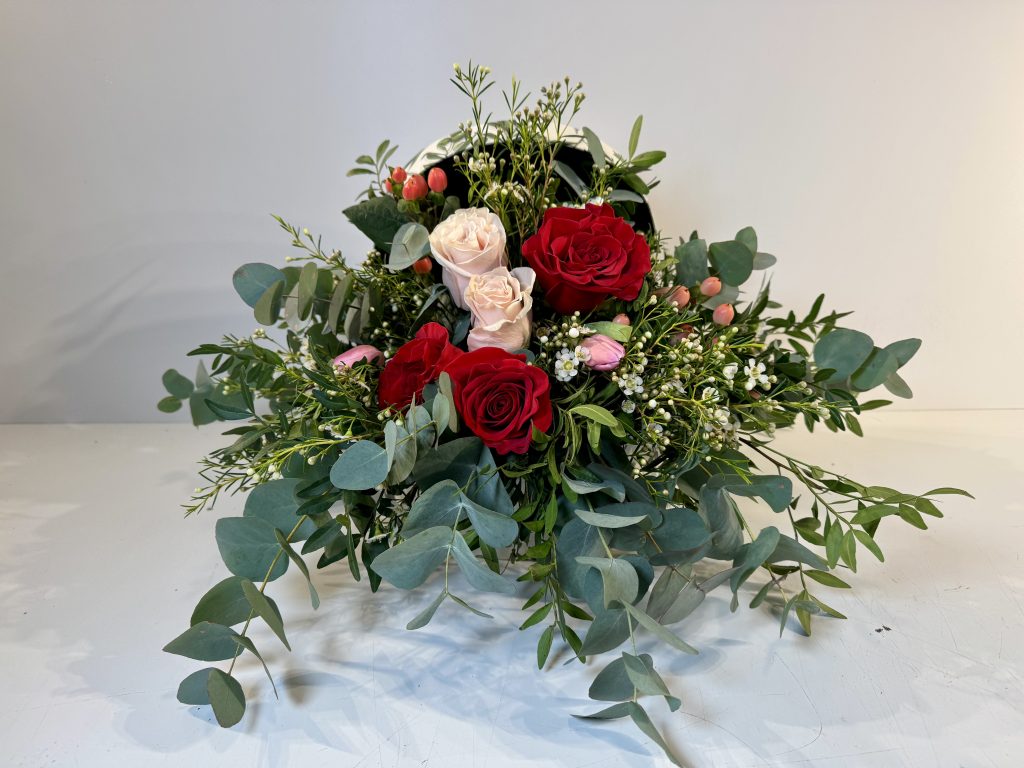 baúl con rosas rojas, rosas y flores en tonos blancos y rosas.