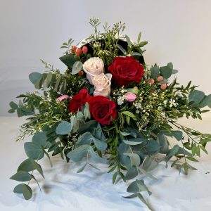 baúl con rosas rojas, rosas y flores en tonos blancos y rosas.