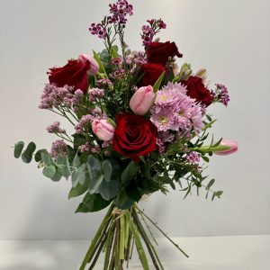 Bouquet de flores en tonos rosas y rojos, con verdes variados