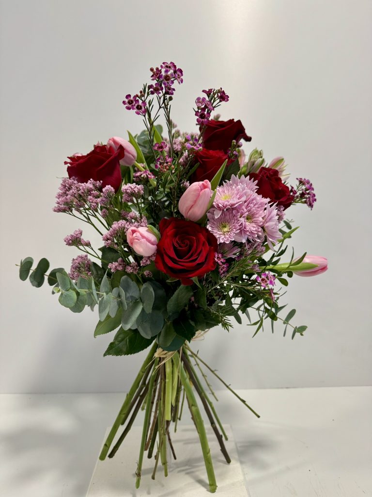 Bouquet de flores en tonos rosas y rojos, con verdes variados