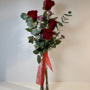 violetero con cuatro rosas rojas con toque de pequeña flor en tonos rosas y verdes