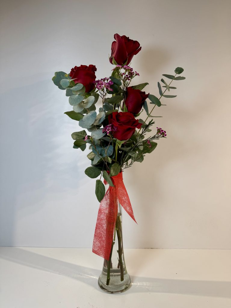 violetero con cuatro rosas rojas con toque de pequeña flor en tonos rosas y verdes