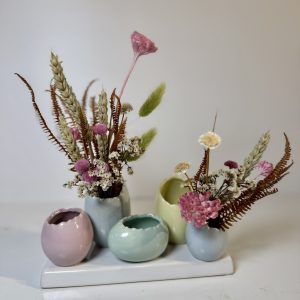 Base con jarroncitos pegados en forma de huevo con flores secas