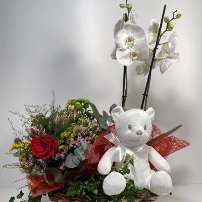 composición para San Valentín de orquídeas, bouquet silvestre y peluche en una cesta de mimbre