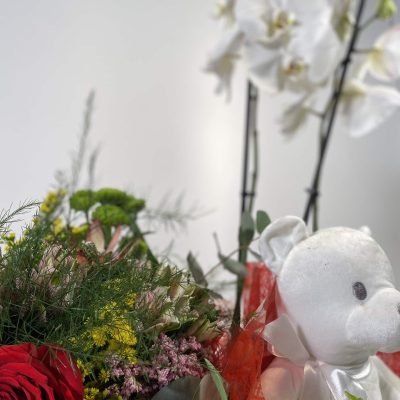 composición para San Valentín de orquídeas, bouquet silvestre y peluche en una cesta de mimbre