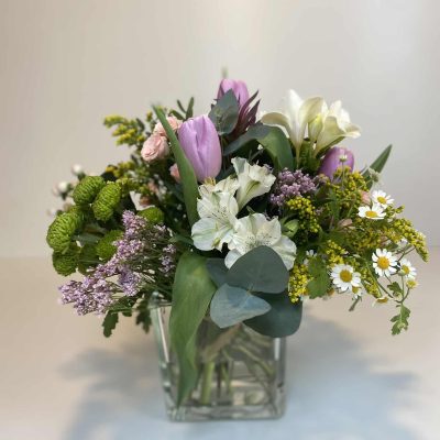 Bouquet silvestre en jarrón de cristal, flores en colores variados.