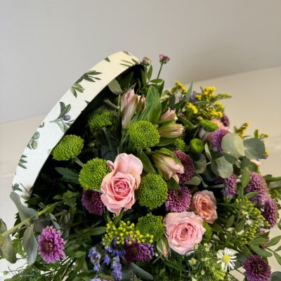 Baúl con flores coloridas de temporada en tonos rosas, morados, verdes y amarillos.