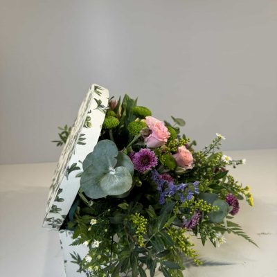 Baúl con flores coloridas de temporada en tonos rosas, morados, verdes y amarillos.